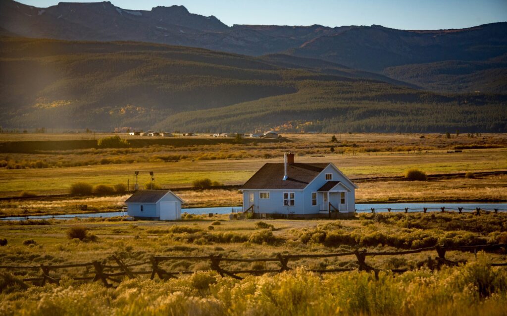 Lone house in open countryside, with wooded hills in the distance.