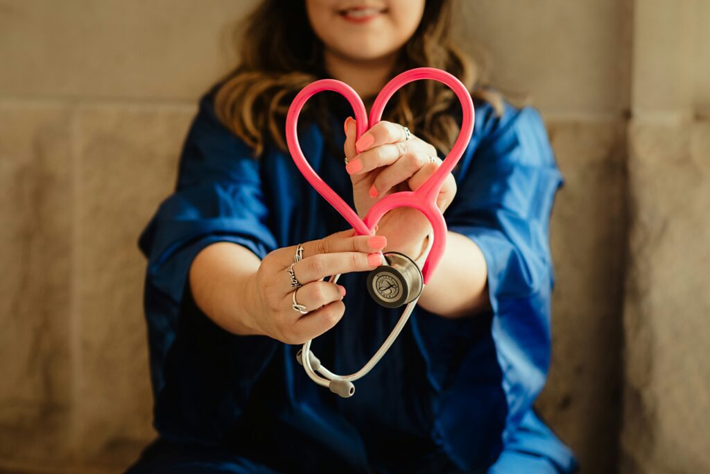 A nurse holding a stethoscope in the shape of a heart.