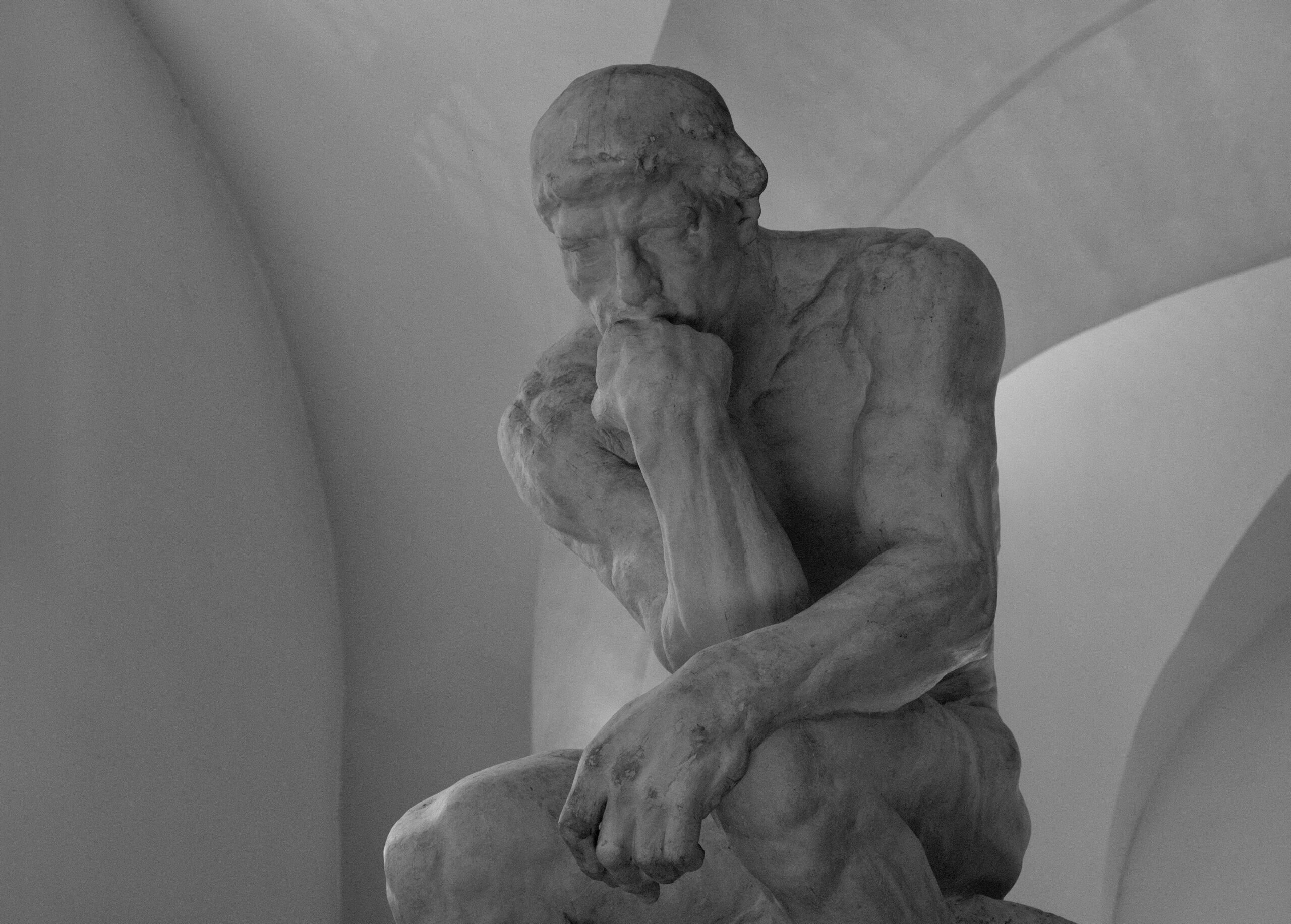 Stone statue of a man pondering existence. 
