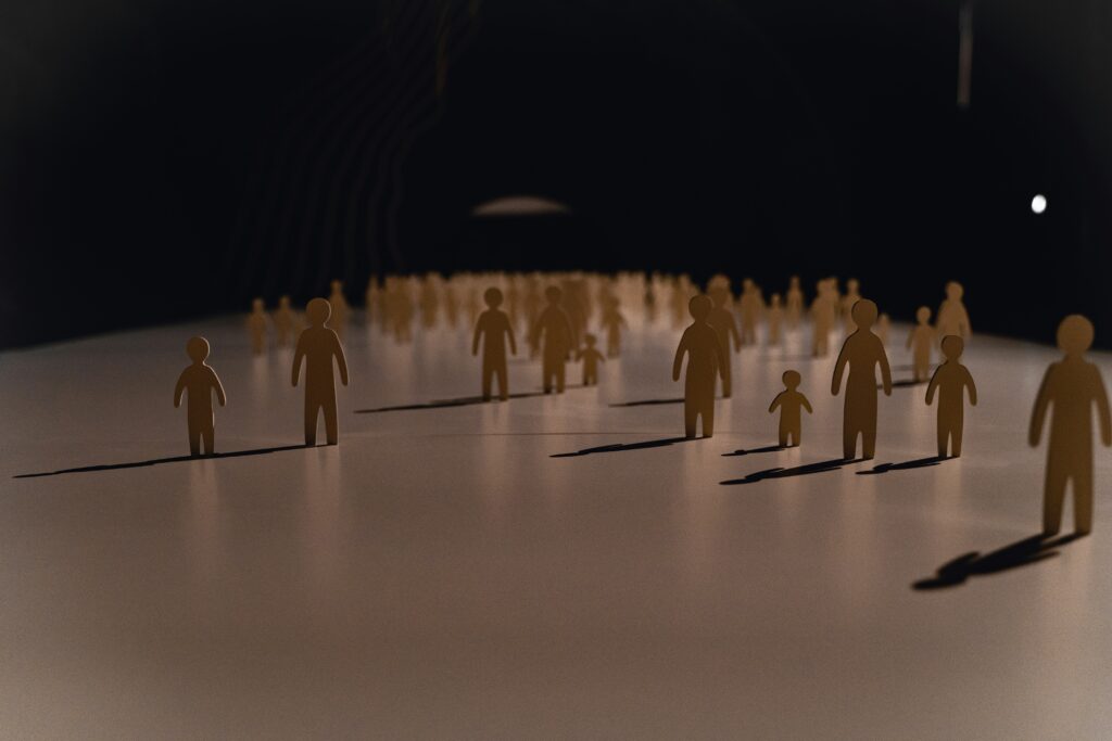 Small wooden models of people standing on a blank surface.