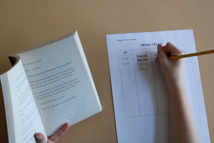 child's hand writing out words and sounds