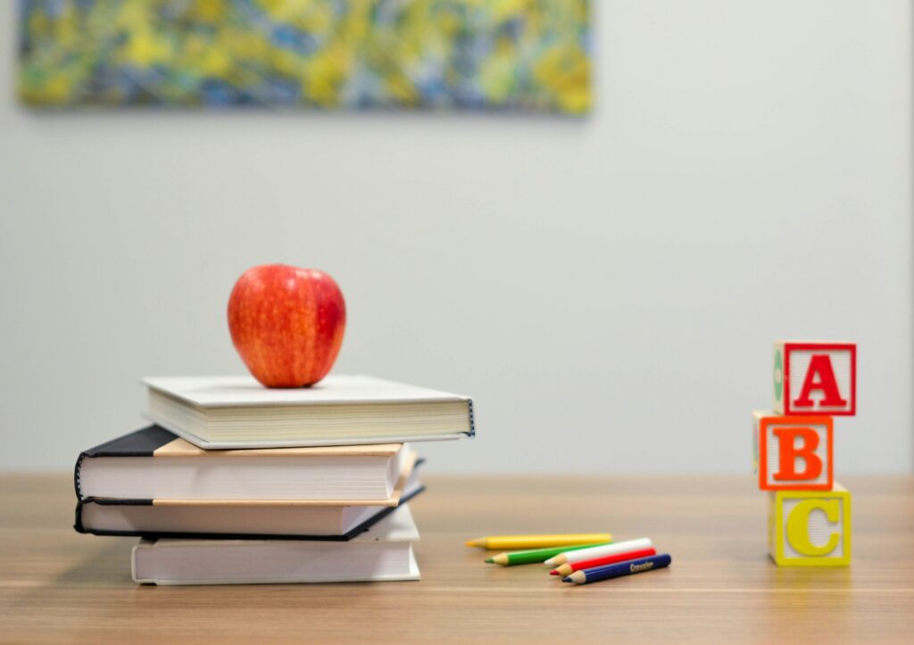 Classroom scene featuring stacked books and other classroom utensils. 